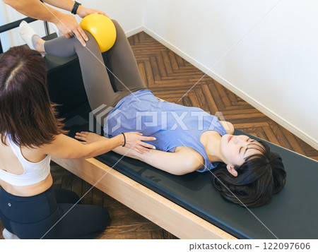 A woman taking a machine pilates lesson A woman taking a machine pilates lesson 122097606