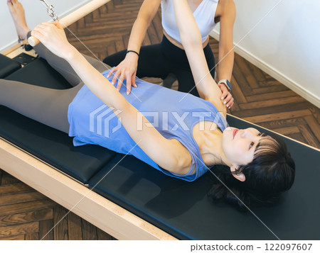 A woman taking a machine pilates lesson A woman taking a machine pilates lesson 122097607