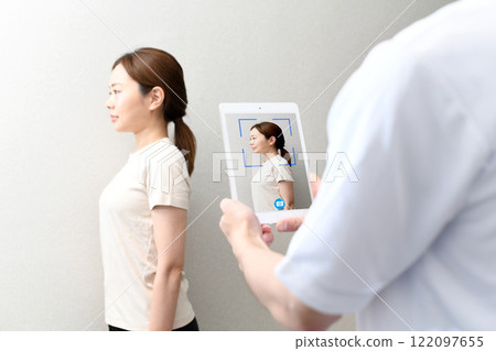A therapist taking a picture of a female patient on a tablet 122097655