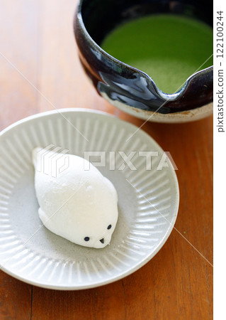 Cup of fresh matcha tea, green tea and Seal shape daifuku Japanese confectionery on wooden table. Cup of fresh matcha tea, green tea and Seal shape daifuku Japanese confectionery on wooden table. 122100244