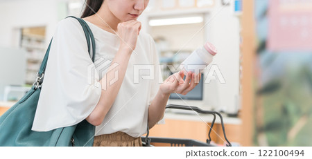A woman shopping at a pharmacy, drug store, or convenience store 122100494