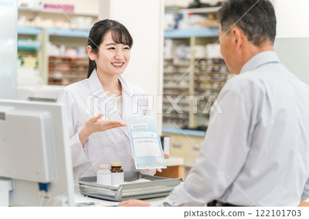 A female pharmacist and an elderly man explaining medicines at the pharmacy cash register 122101703