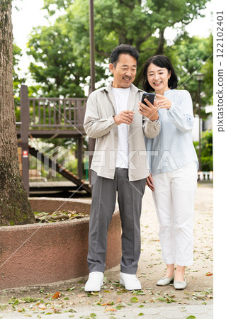 一對中年夫婦在智慧型手機上進行研究的生活方式形象 一對中年夫婦在智慧型手機上進行研究的生活方式形象 122102401