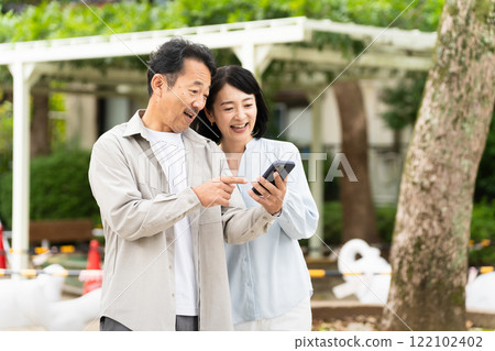 一對中年夫婦在智慧型手機上進行研究的生活方式形象 122102402