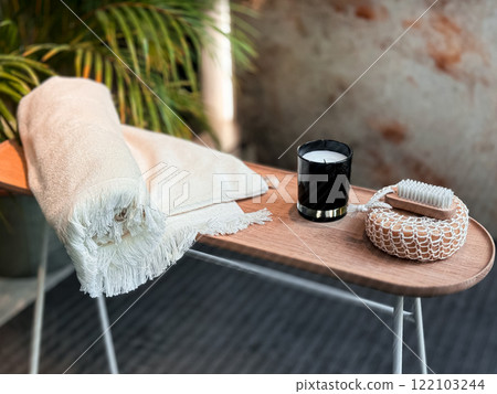 Luxurious spa setting with towel, candle, and brush on wooden table Luxurious spa setting with towel, candle, and brush on wooden table 122103244