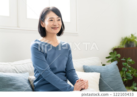 Middle-aged woman sitting on the sofa Lifestyle image 122103433