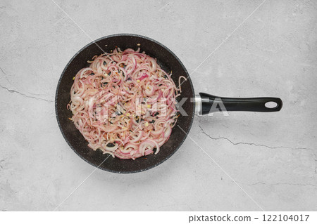 Cooking thinly sliced red onions in a pan for a flavourful base in a savoury dish Cooking thinly sliced red onions in a pan for a flavourful base in a savoury dish 122104017
