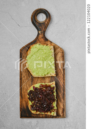Creamy avocado spread and savory onion relish on toasted bread served on a wooden board Creamy avocado spread and savory onion relish on toasted bread served on a wooden board 122104020