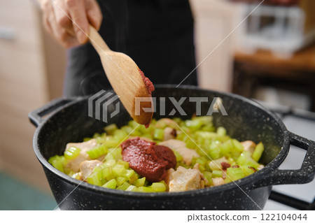 Cooking celery and meat with tomato paste in a pot during meal preparation in a kitchen 122104044