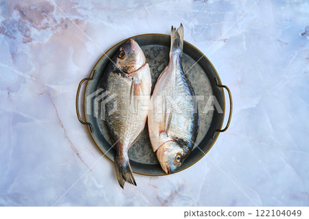 Top view of two fresh dorado fish lie side by side on a round metal tray 122104049