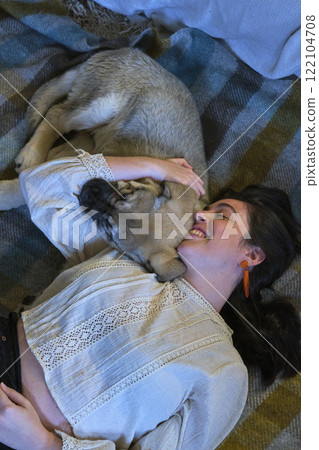 Young woman embracing puppy on blanket at home: showing affection and happiness 122104708
