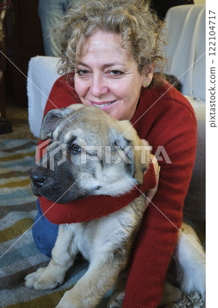 Smiling mature woman hugging puppy at home 122104717