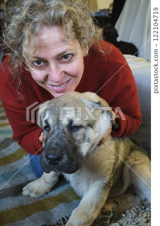 Smiling mature woman cuddling adorable puppy at home 122104719