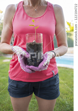 Gardener holding holly sprout growing in glass jar 122104722