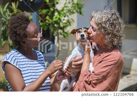 Mother kissing dog while daughter is looking at them 122104766
