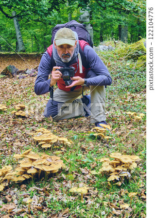 Photographer taking pictures of mushrooms in the forest Photographer taking pictures of mushrooms in the forest 122104776