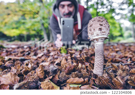 Explorer Photographing a Macrolepiota Procera Mushroom in a Beech Forest Explorer Photographing a Macrolepiota Procera Mushroom in a Beech Forest 122104806