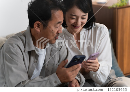 A middle-aged couple doing research on a smartphone Lifestyle image 122105633
