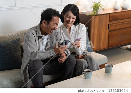 A middle-aged couple doing research on a smartphone Lifestyle image 122105634