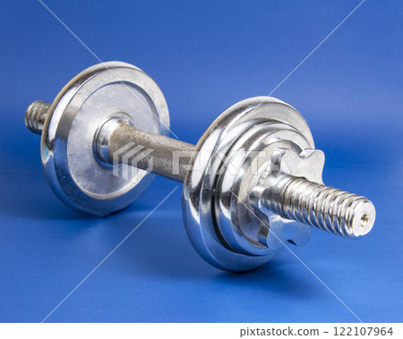 Stainless metal dumbbell on dark blue background with copyspace for text 122107964