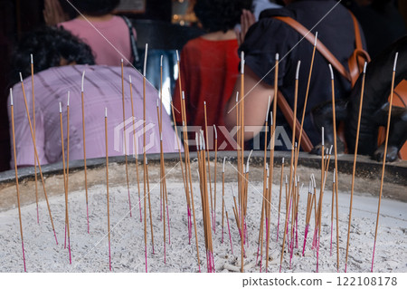 Burning incense candles in a pot in the temple, with blurred background of people praying Burning incense candles in a pot in the temple, with blurred background of people praying 122108178
