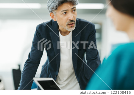 一位頭髮花白的中年男子在會議上發言 一位頭髮花白的中年男子在會議上發言 122108416