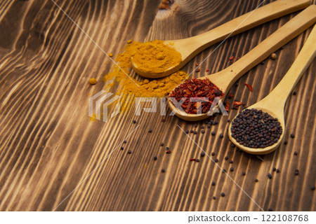 Dry different spices in spoons on wooden background Dry different spices in spoons on wooden background 122108768