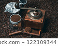 Rustic coffee grinder with a measuring spoon and an espresso maker with many coffee beans 122109344