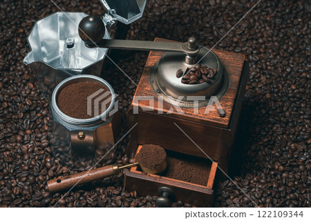 Rustic coffee grinder with a measuring spoon and an espresso maker with many coffee beans 122109344