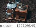 Rustic coffee grinder with a measuring spoon and an espresso maker with many coffee beans 122109345