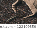 Jute sack full of coffee with a golden coffee scoop on a background of coffee beans 122109350