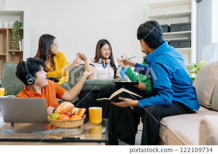 Asian college student reading a book study on laptop prepare for the exam or work on a group project at home. Asian college student reading a book study on laptop prepare for the exam or work on a group project at home. 122109734