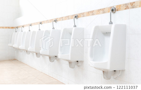 Men's room with white porcelain urinals in line. Modern clean public toilets with tiles . Comfort male toilet urinal concept. Men's room with white porcelain urinals in line. Modern clean public toilets with tiles . Comfort male toilet urinal concept. 122111037