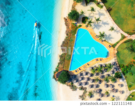 Aerial view of pool, sandy beach, umbrellas, boat, blue sea 122111148