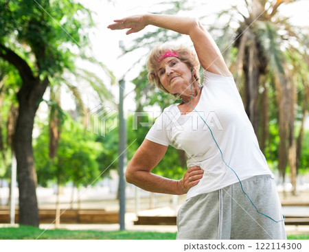 Elderly woman stretches in a park 122114300