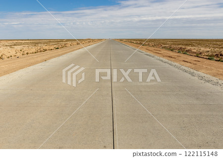 Long concrete road stretches through the vast landscape of Karakalpakstan in Uzbekistan 122115148
