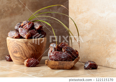 Dates fruit in a wooden dish on a beige table. Dates fruit in a wooden dish on a beige table. 122115170