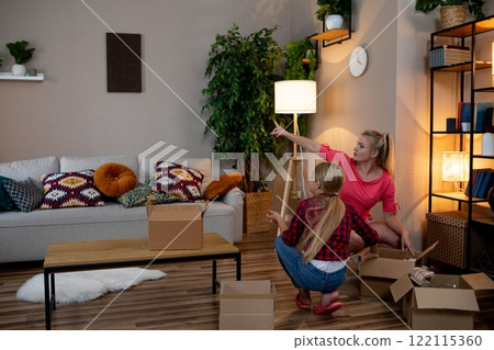 There are Two Women Carefully Arranging Furniture in a Cozy and Inviting Living Room Space There are Two Women Carefully Arranging Furniture in a Cozy and Inviting Living Room Space 122115360