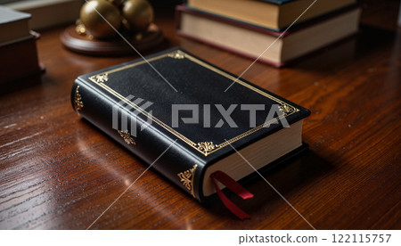Elegant black leather book resting on polished wooden table amidst other stacked books and decorative objects Elegant black leather book resting on polished wooden table amidst other stacked books and decorative objects 122115757