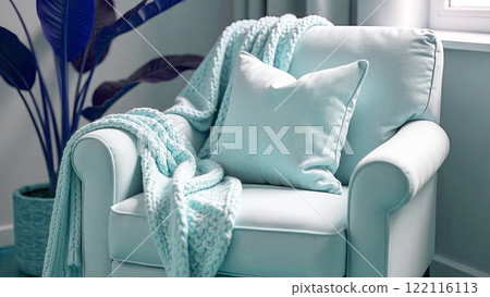Cosy armchair with thick knitted plaid in light blue colour and cushion. Home decor in a romantic style. Cosy armchair with thick knitted plaid in light blue colour and cushion. Home decor in a romantic style. 122116113
