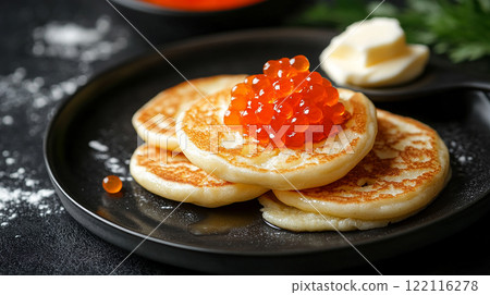Russian A plate of pancakes with a garnish of caviar on top. The plate is black and the caviar is red 122116278