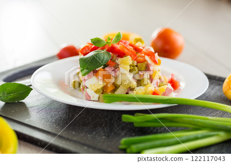 vegetable salad of boiled vegetables, with peas, sausage, sweet pepper. On a wooden table 122117043