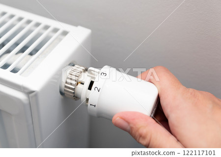 Person is adjusting the temperature on a radiator Person is adjusting the temperature on a radiator 122117101