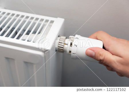 Person is adjusting the temperature on a radiator Person is adjusting the temperature on a radiator 122117102