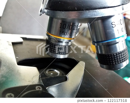 Microscope lens in the laboratory. Metal specimen clamp. Lens with yellow stripe and blue. 122117318