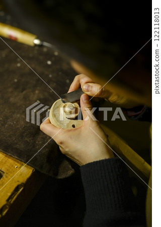 Luthier carefully carving violin scroll in workshop Luthier carefully carving violin scroll in workshop 122118013