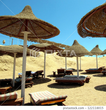 Relaxing on the Beach Under Wicker Umbrellas by Red Sea During a Sunny Day, Sharm El Sheikh, Egypt Relaxing on the Beach Under Wicker Umbrellas by Red Sea During a Sunny Day, Sharm El Sheikh, Egypt 122118015