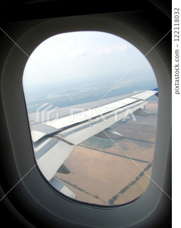 View From a Plane Porthole Showcasing the Wing Above Sprawling Agricultural Fields Below 122118032
