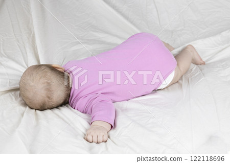 4-month-old baby girl laying on bed and crying. Infant  in pink clothes wants to sleep 122118696