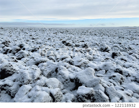 A field of black soil plowed for the winter, covered with snow against the background of a blue winter sky 122118932